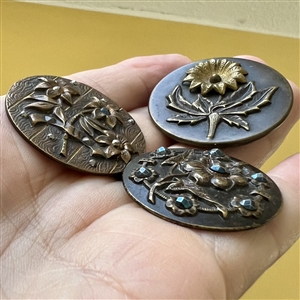 Three Victorian brass buttons of flowers.