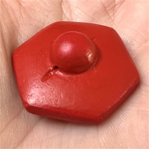 Modern hexagon “cinnabar” button of plant life over a background of squares.