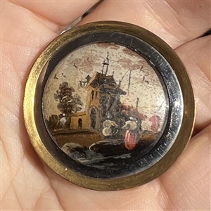 An 18th c. painting under glass of a village scene with people button.