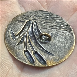 Brass button of cattails and cut steel ducks.