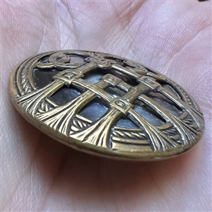 Iridescent pearl button with stylized brass design.