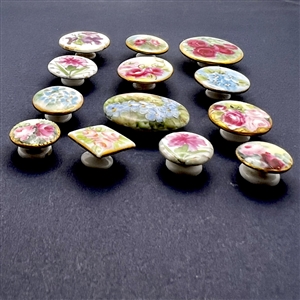 Thirteen painted porcelain studs of flowers.