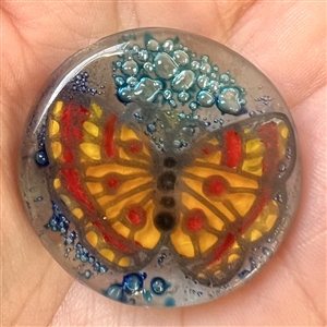 Contemporary fused glass button from an artist in Ecuador of a colorful butterfly.