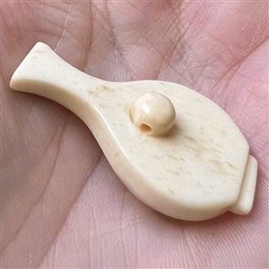 Carved natural material button of a vase.