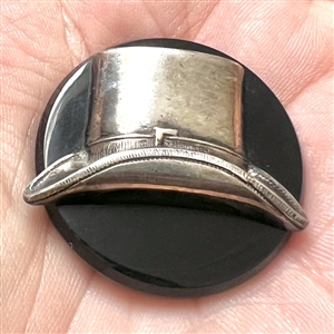 Vintage casein button with silvered metal escutcheon of a top hat.