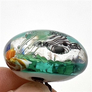 Glass paperweight studio button of fish swimming.