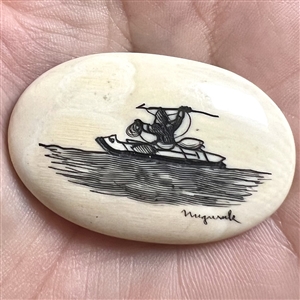 Scrimshaw button of an Eskimo spear hunting from a kayak on natural material.