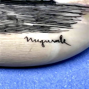 Scrimshaw button of an Eskimo spear hunting from a kayak on natural material.