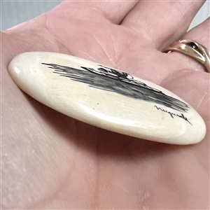 Scrimshaw button of an Eskimo spear hunting from a kayak on natural material.
