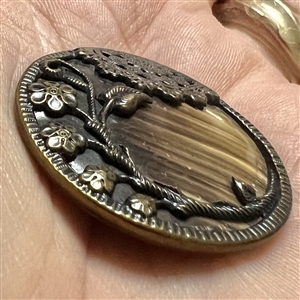 Victorian celluloid button set in tinted brass with flowers and lace.