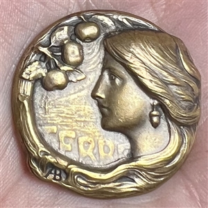 Art Nouveau brass button of a woman with verbal “Terre (earth) by Armond Bargas.