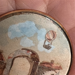 Architectural and hot air balloon scene, gauche on paper under glass set in metal button.