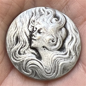 Art Nouveau style Battersea pewter button of a woman with flowing hair.