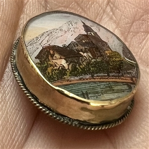 Reverse-painted architectural scene under glass set in gilded metal button.