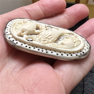 Carved natural material button of lions attacking a deer (?).