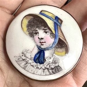 Porcelain button of a girl in straw hat with blue ribbon.