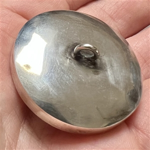 Incised, inked and painted natural material button of two fish swimming.