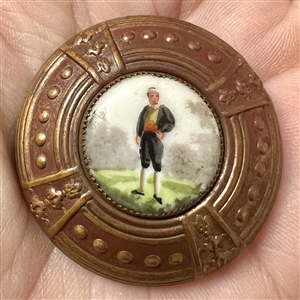 Painted porcelain button of a young man in short pants and puffy sleeves.