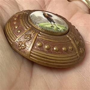 Painted porcelain button of a young man in short pants and puffy sleeves.