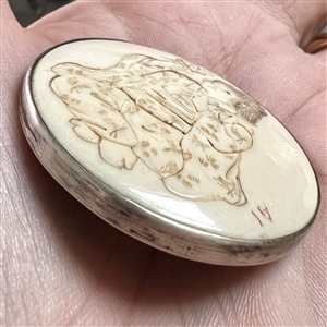 Incised, inked or painted natural material button of an Asian girl with a flower.