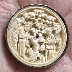 Carved natural material button of two Asian figures in a garden