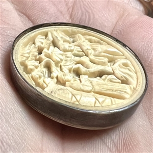 Carved natural material button of two Asian figures in a garden