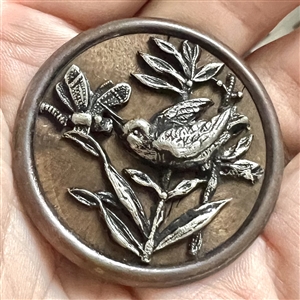 White metal bird and dragonfly over wood button. 