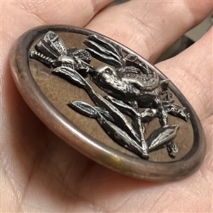 White metal bird and dragonfly over wood button. 