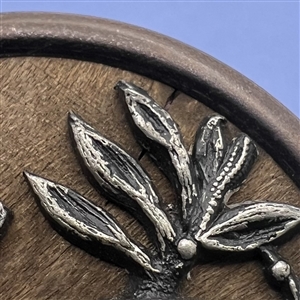 White metal bird and dragonfly over wood button. 