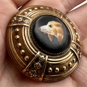 Ceramic button of a dog set in brass.