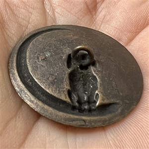 Tinted brass button of a poodle.