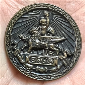 Brass button of Putti holding a torch while riding a griffin.