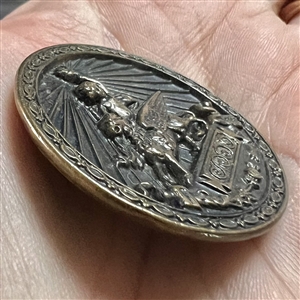 Brass button of Putti holding a torch while riding a griffin.