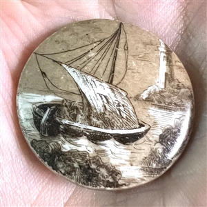 Porcelain button of a sailing ship near shore.