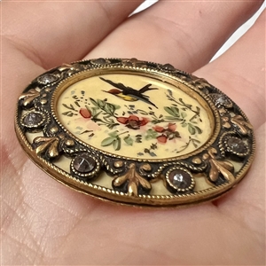 A Victorian painted bird in flight on celluloid set in metal with cut steels button.