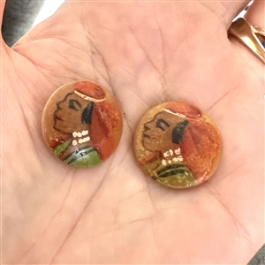 Two painted vegetable ivory buttons of heads.