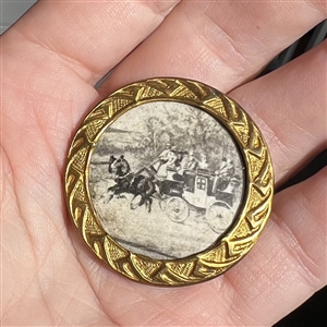 Printed paper under celluloid of a horse and carriage. 