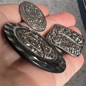 Three black glass buttons with silver luster.