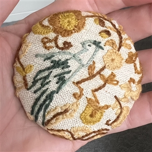 Huge embroidered studio button of bird in a flower garden by Marie Boorum. 