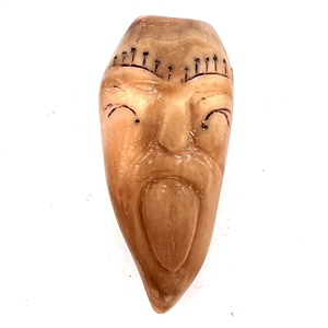 Carved fossilized tooth button of a tattooed mans face with tongue out.