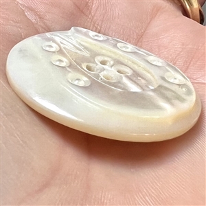 Carved ocean pearl button of a horseshoe.
