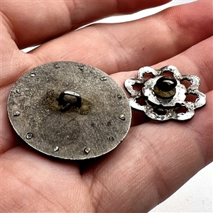 Two steel and pearl buttons.