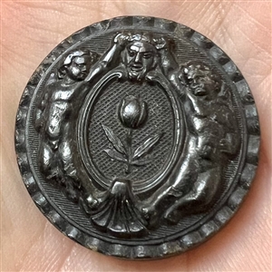 Horn button of putti holding horns of mask of Pan.