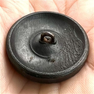 Horn button of putti holding horns of mask of Pan.