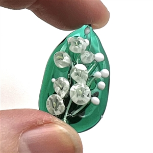 Mary Gaumond's white lily of valley flowers on a leaf studio button.