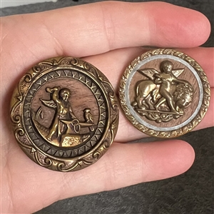 Two brass buttons with wood backgrounds of Cupid.