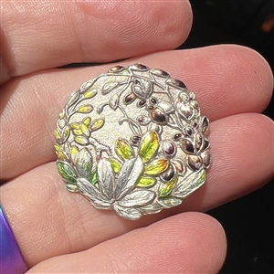 Japanese enamel button of flowers in a garden.
