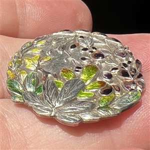 Japanese enamel button of flowers in a garden.