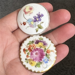 Two painted porcelain buttons of flowers. 