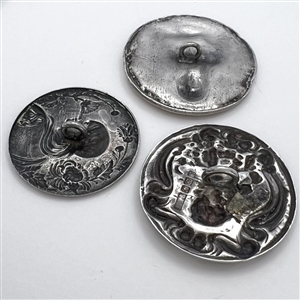 Three metal buttons of women, with one of them by Armond Bargas.
